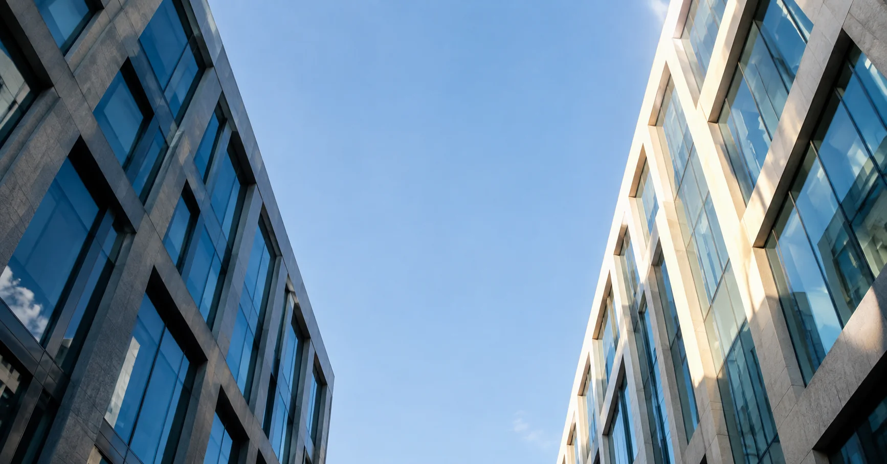 Fachadas contemporáneas enmarcan una abertura de cielo azul.