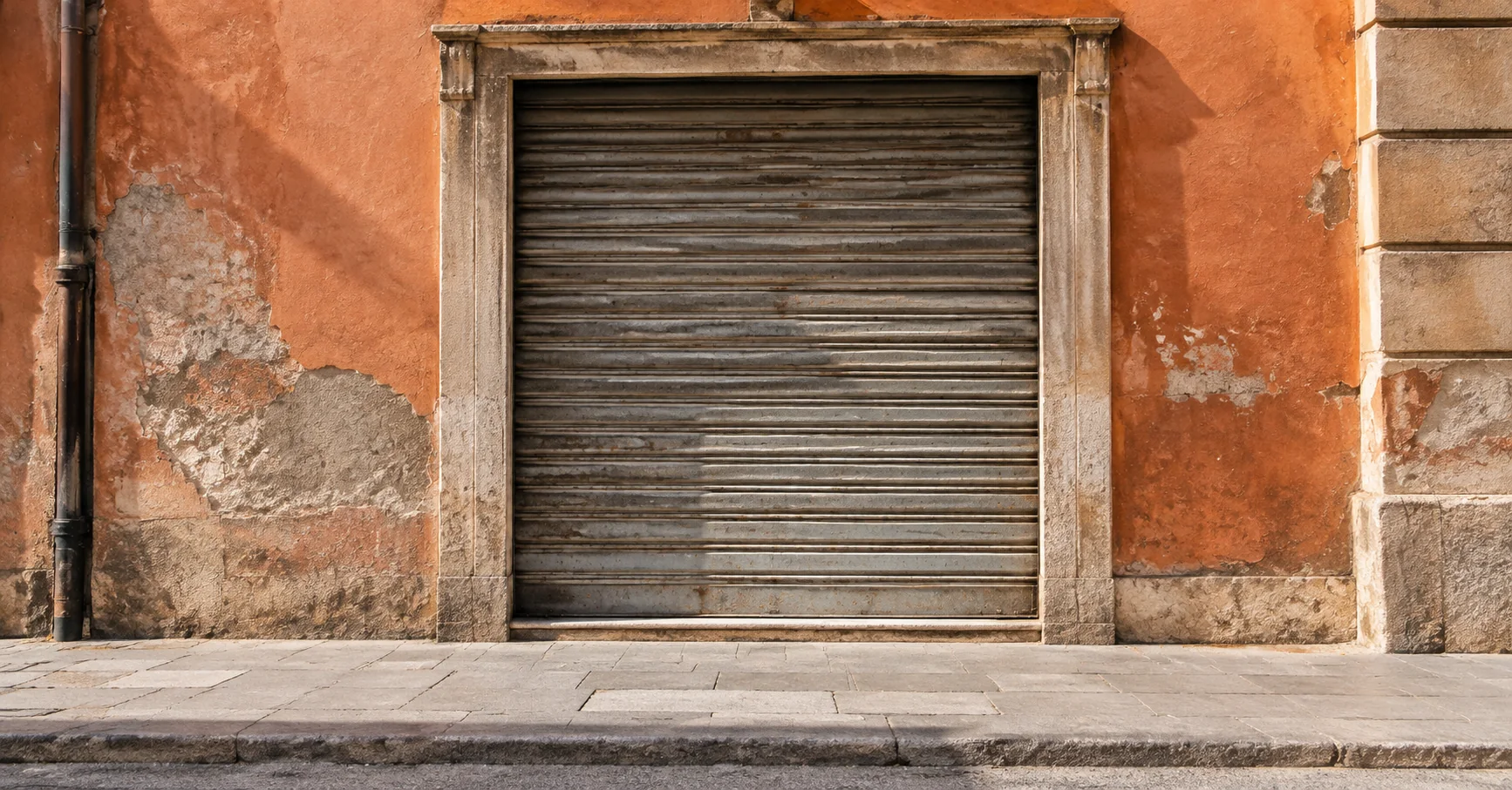 La persiana cerrada de un antiguo local en una calle tranquila.