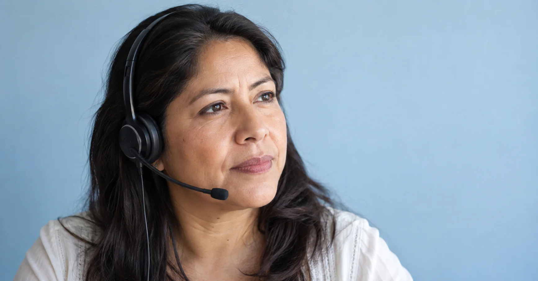 Retrato de una profesional de atención al cliente que escucha con audífonos.